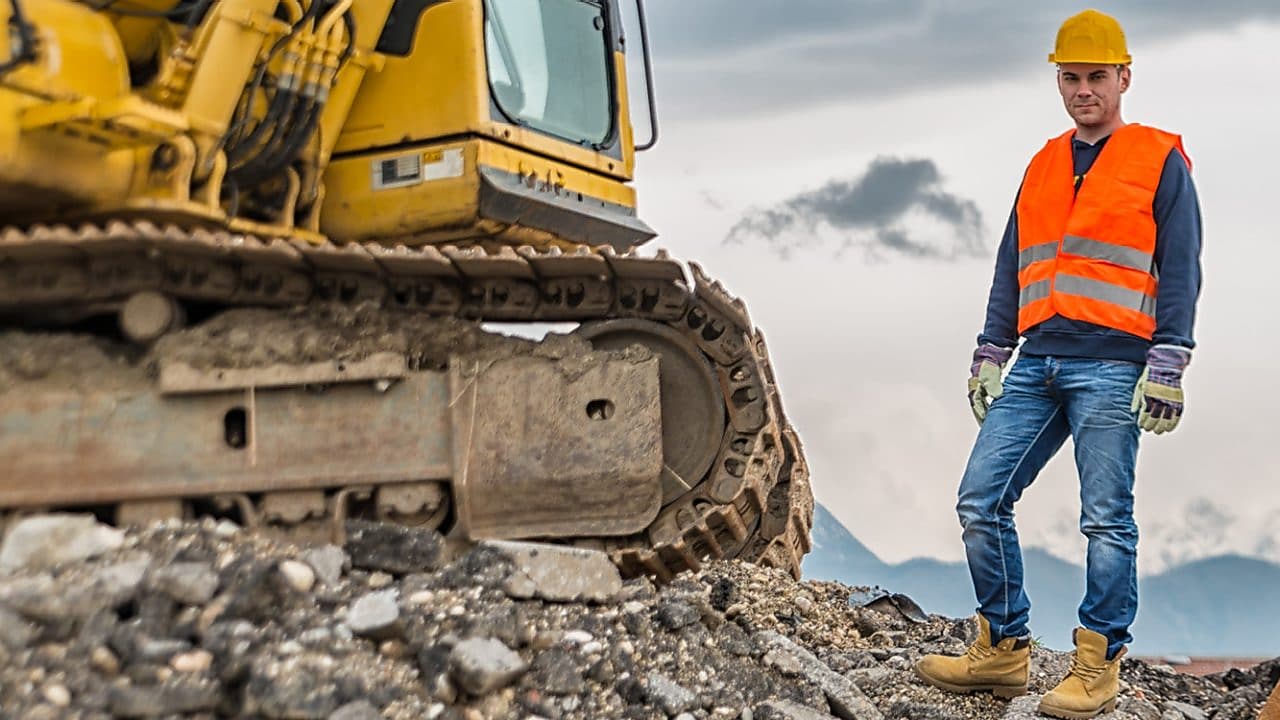 Shell Construction worker standing next to tracked excavator