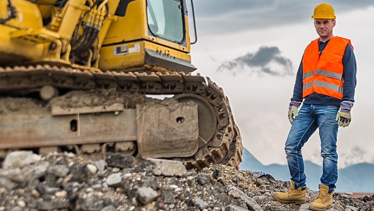 Shell Construction worker standing next to tracked excavator