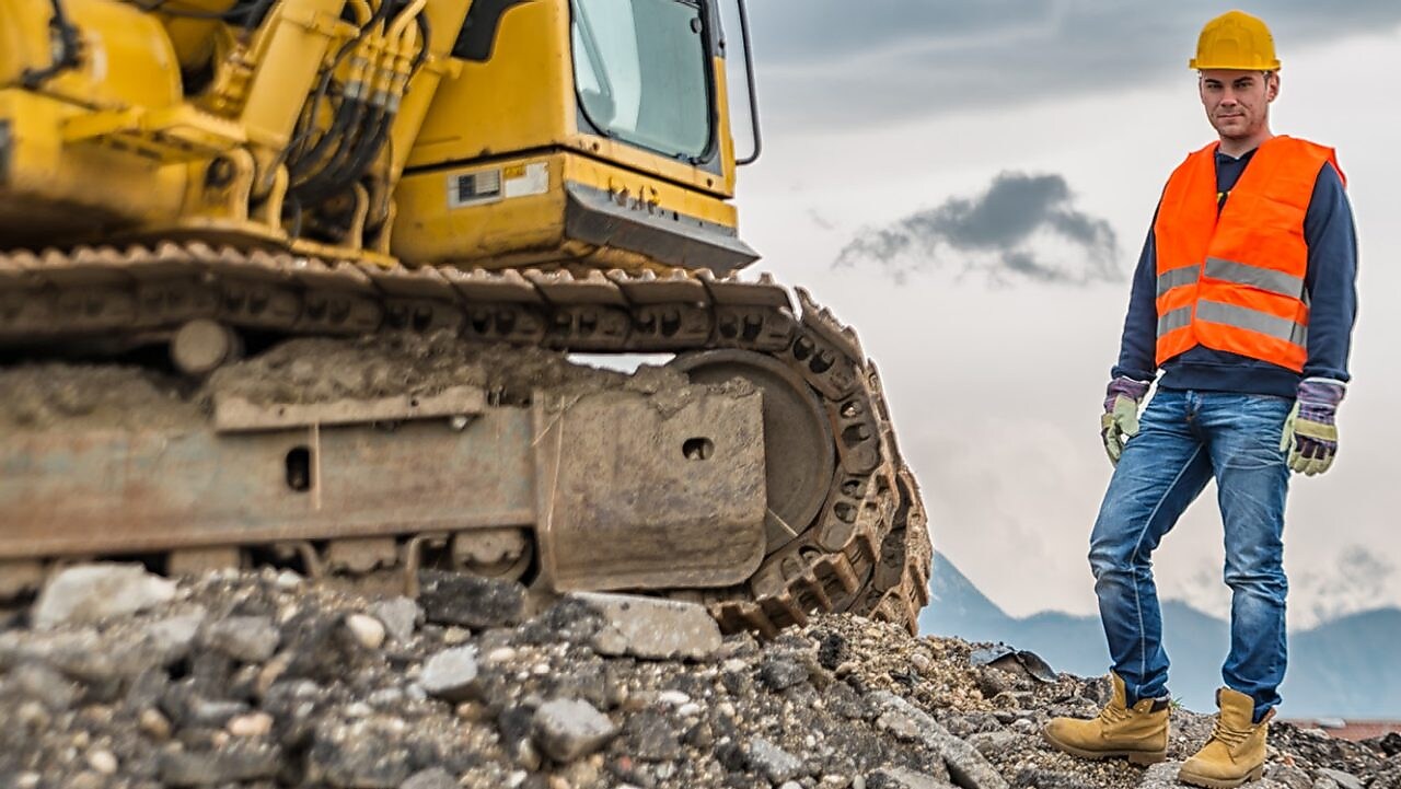 Shell Construction worker standing next to tracked excavator