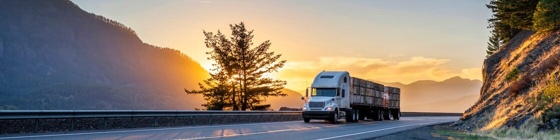 Truck driving on road at sunset