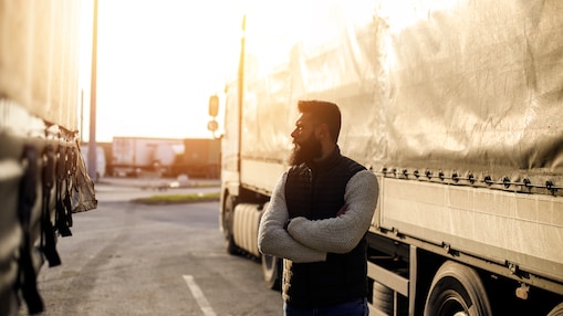 Man standing beside truck trailer with arms crossed
