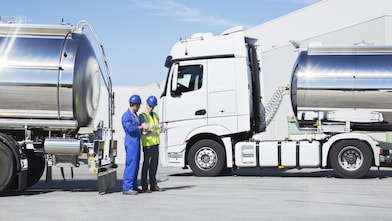Workers talking next to two tanker lorries
