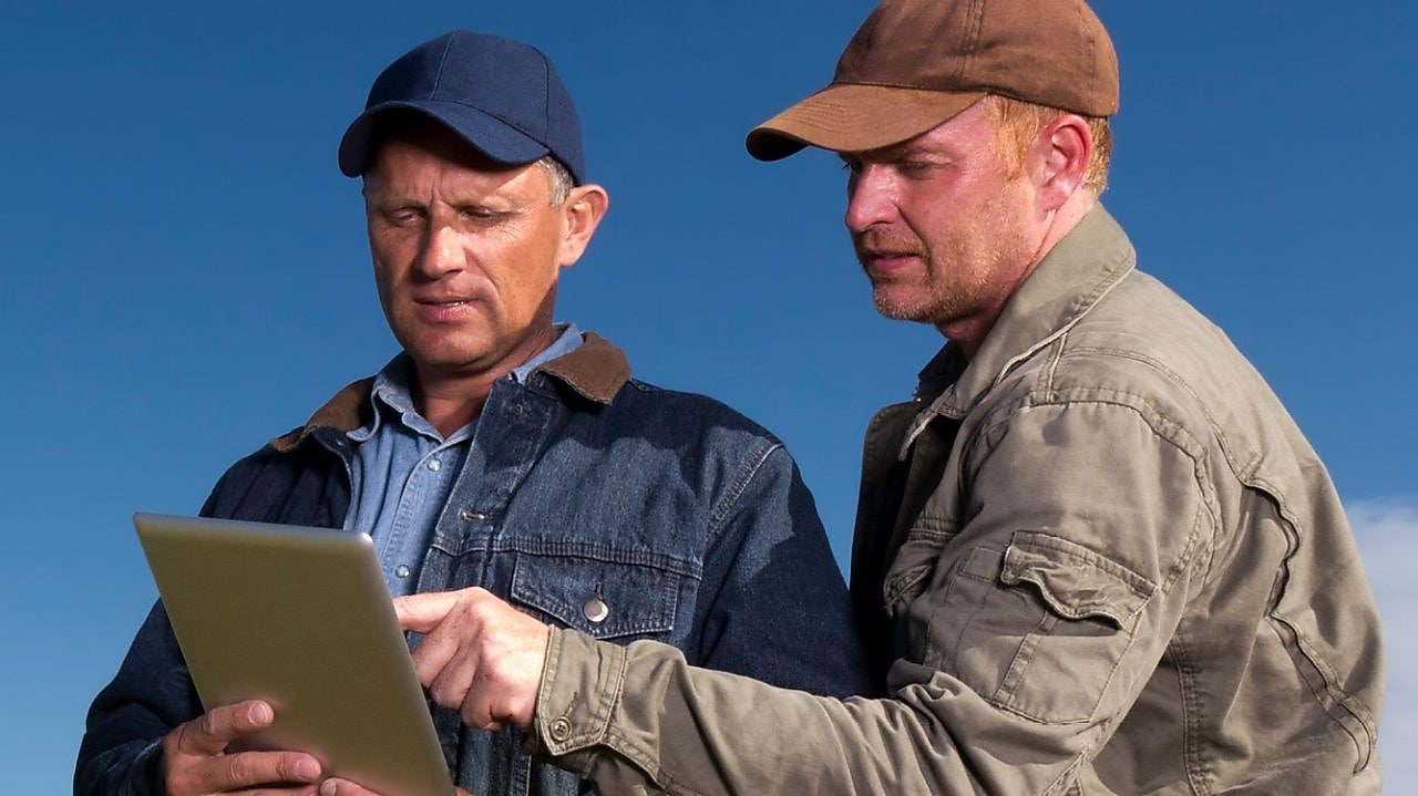 Two farmers looking at a tablet