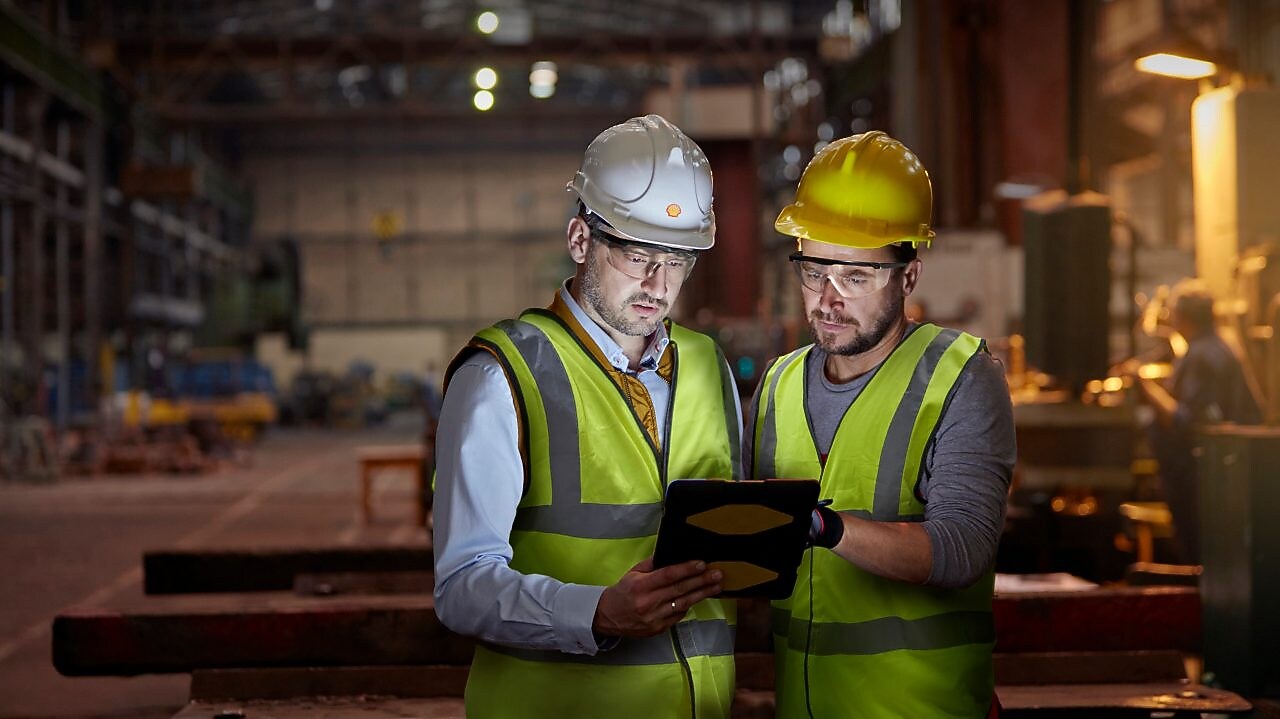 Male engineer and worker using digital tablet in dark factory