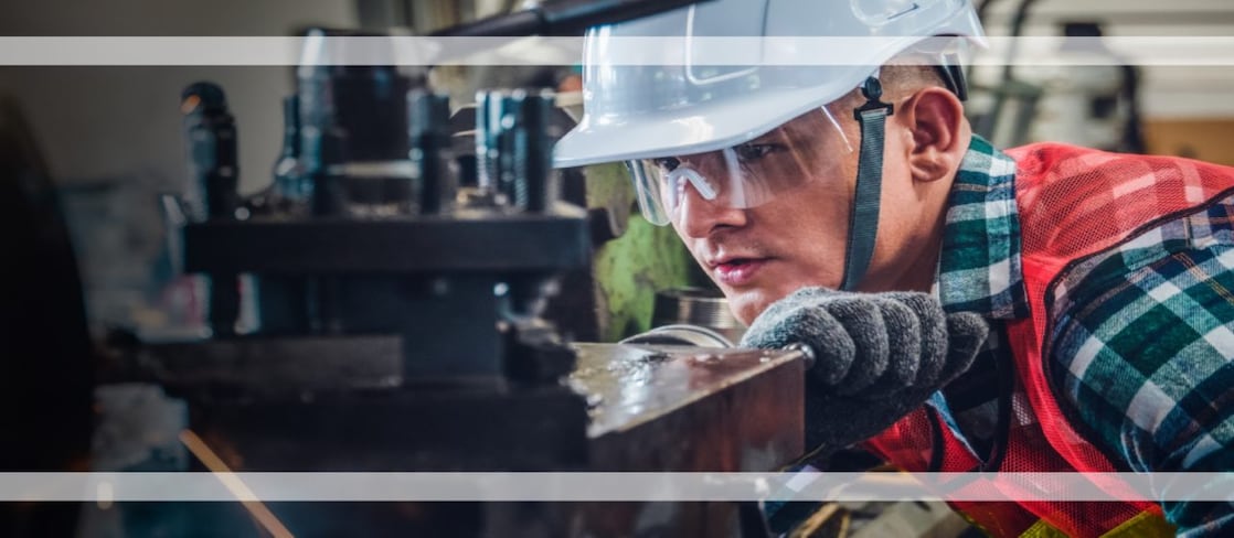 Man with hard hat using a piece of machinery