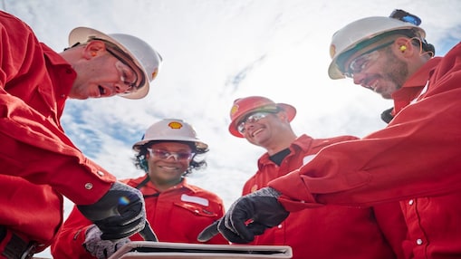 Shell team members in red coveralls having a meeting