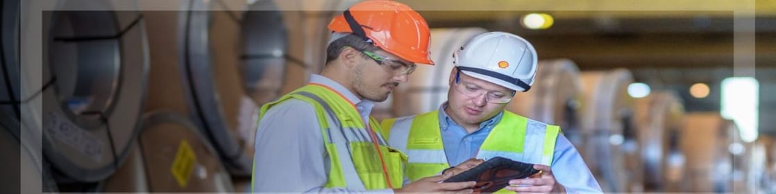 Plant worker on a steel mill on the phone reviewing a document
