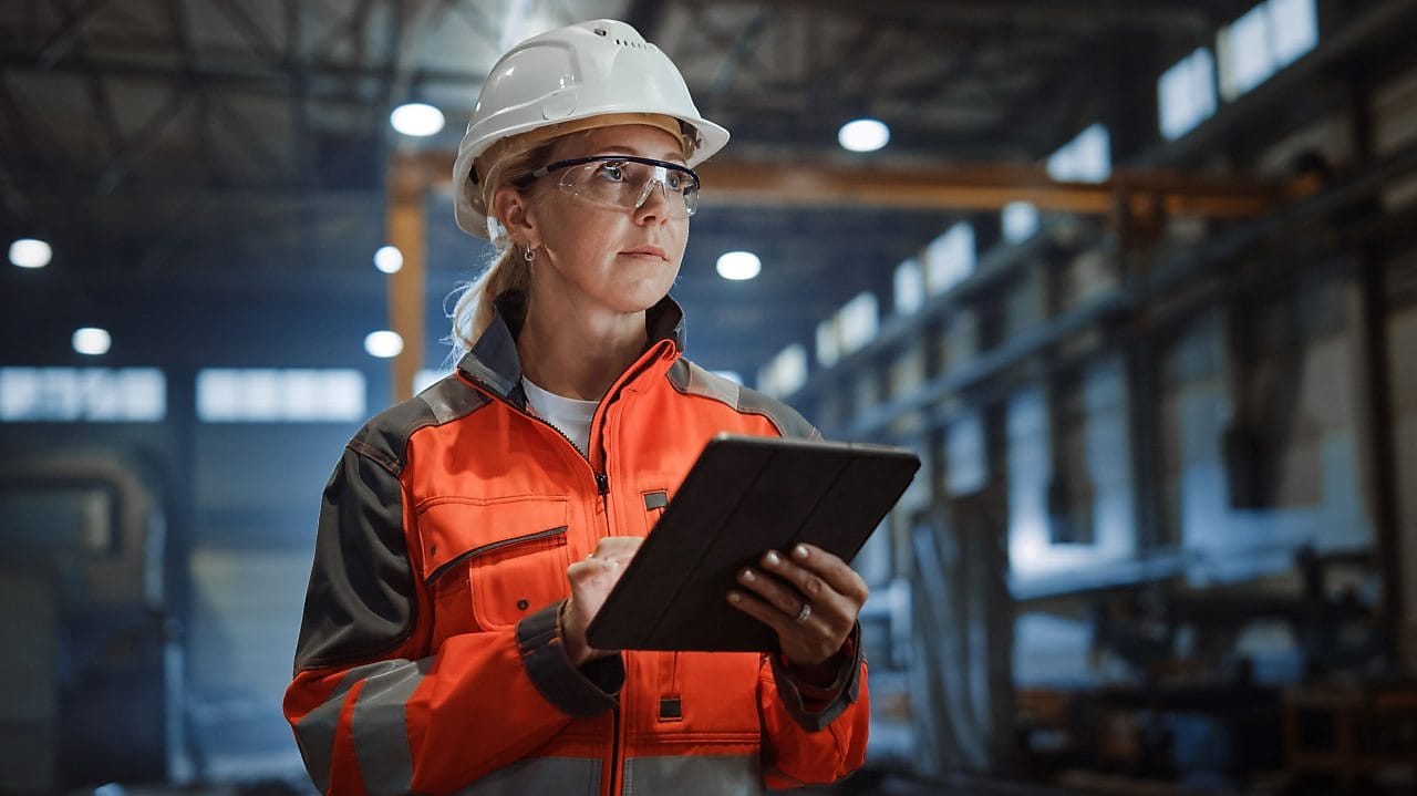 woman in a steel mill in PPE with a clipboard