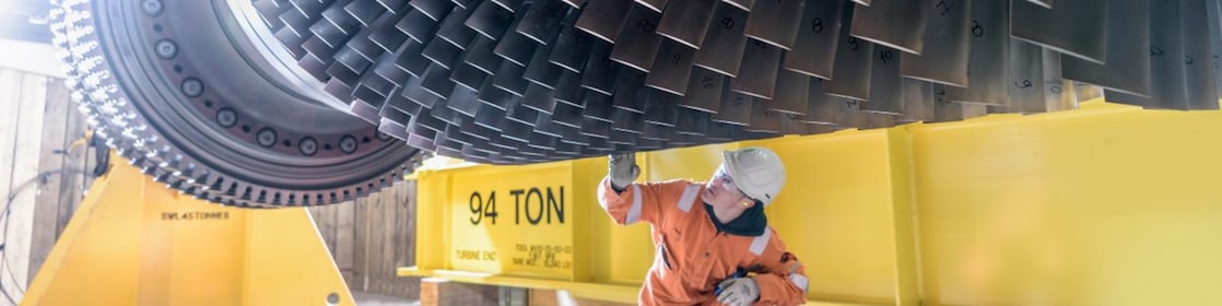 A power engineer inspects the blades of an industrial wind turbine.