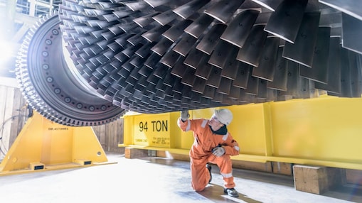 A power engineer inspects the blades of an industrial wind turbine.