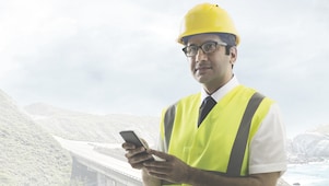 Man wearing a yellow safety helmet holding a phone