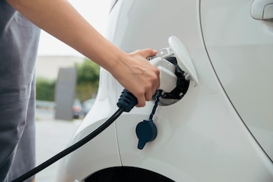 a hand holding an electric vehicle charger, charging a vehicle