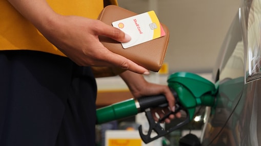 A driver holding the Shell Card filling up a gas station