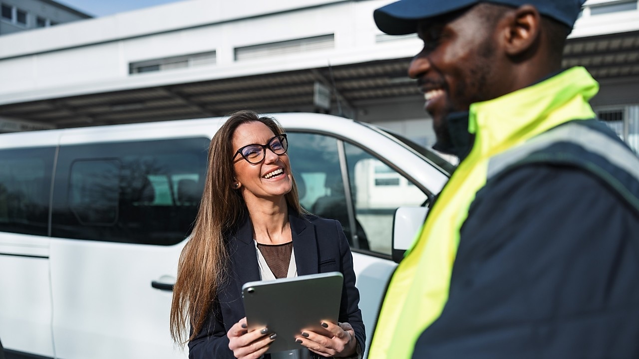 Fleet manager carrying a tablet while speaking to a fleet driver
