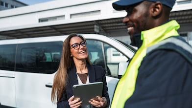 Fleet manager carrying a tablet while speaking to a fleet driver