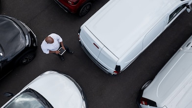 A person standing in a parking lot with cars