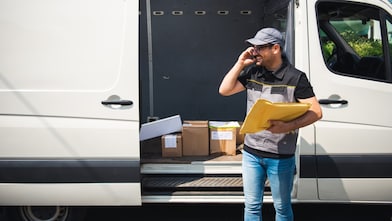 A person holding a clipboard and a file in front of a van