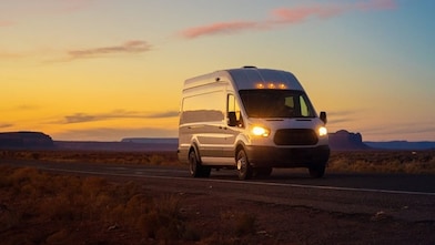 Truck driving on an open road at sunset