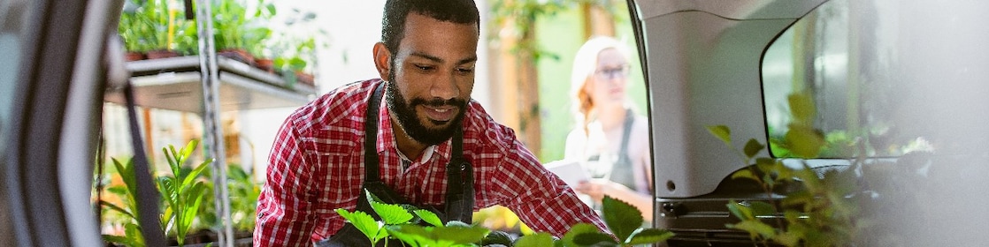 A person in an apron with plants in the back of a van