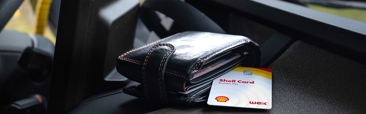 A wallet and shell card on car dashboard