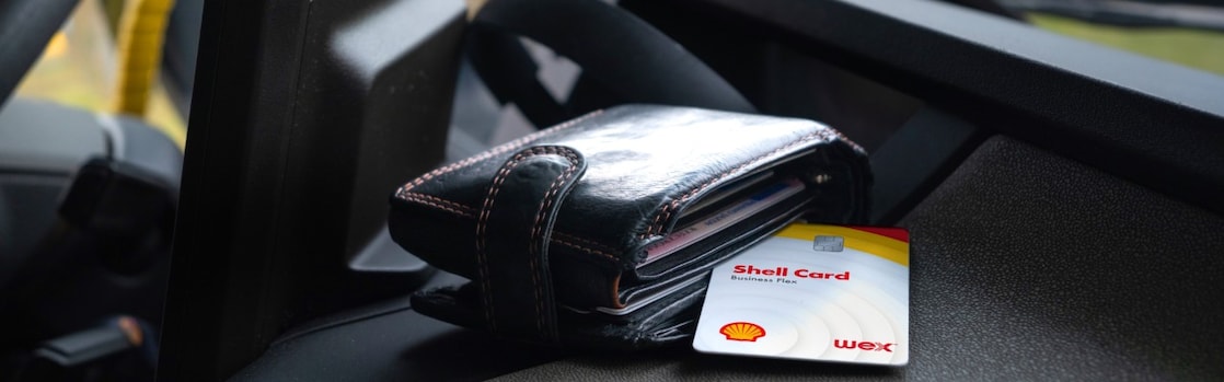 A wallet and shell card on car dashboard