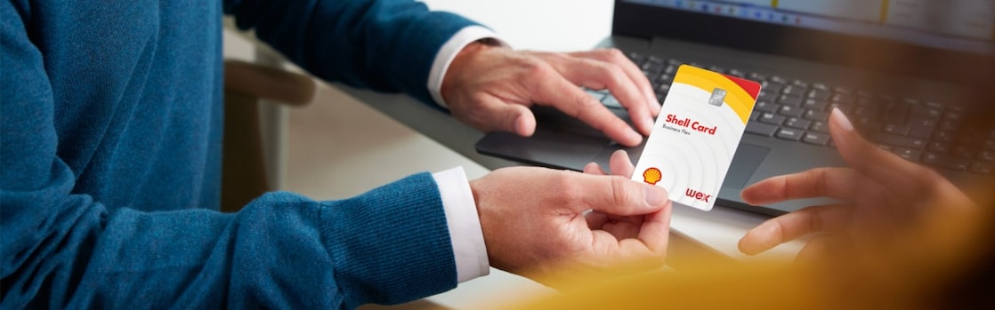 A person handing a Shell Card to another in an office