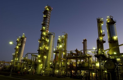 a refinery at dusk, with lights on