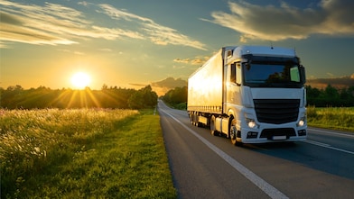 truck on a road next to a forest