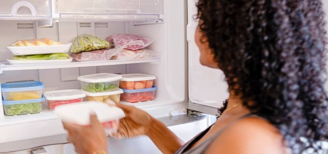 Woman reaching for food in fridge 