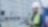 A man in an industrial setting wearing a construction hardhat