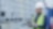 A man in an industrial setting wearing a construction hardhat
