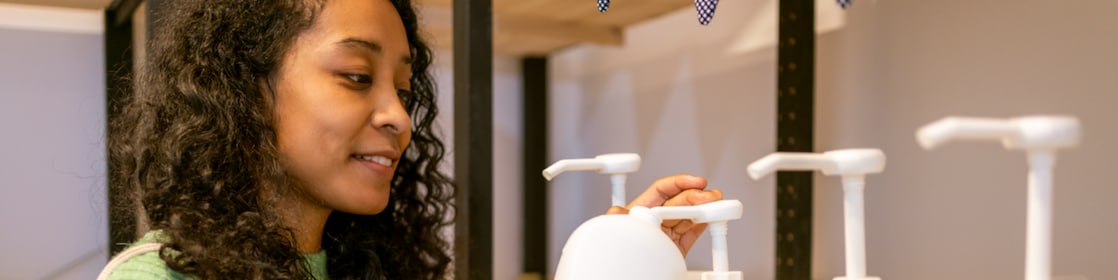 young woman placing soap in white bottle
