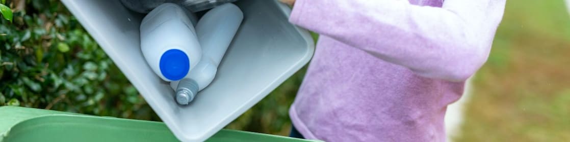 Woman pours household sustainable plastic packaging into recycling bin