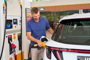 Man fueling a white vehicle at a shell station