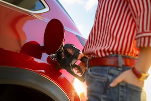 Woman filling up her red vehicle with gas
