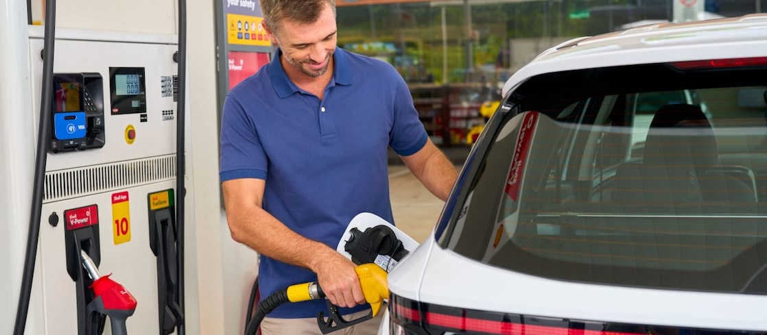 man fueling a white vehicle at a shell station