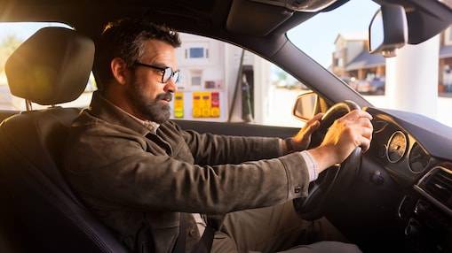 Man with hands on the steering wheel at a shell gas station