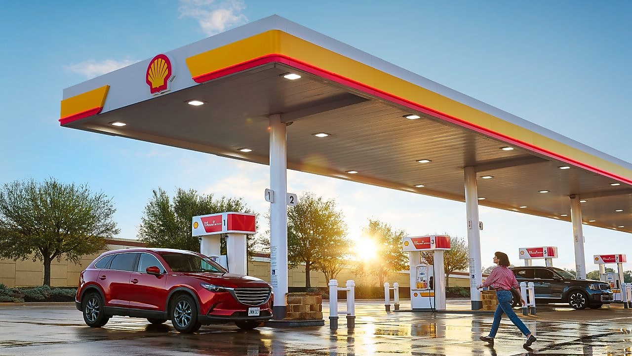 woman walking across the parking lot at a shell station