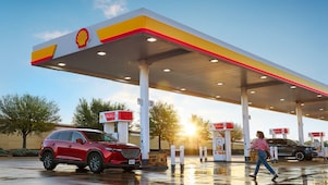 woman walking across the parking lot at a shell station