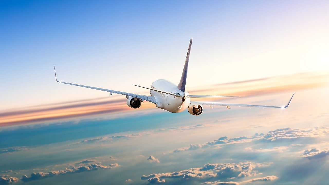 Commercial airplane flying above clouds in dramatic sunset light