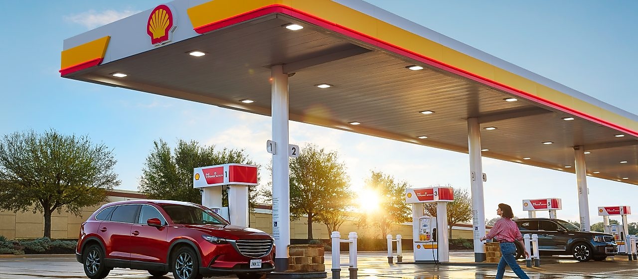woman walking across the parking lot at a shell station
