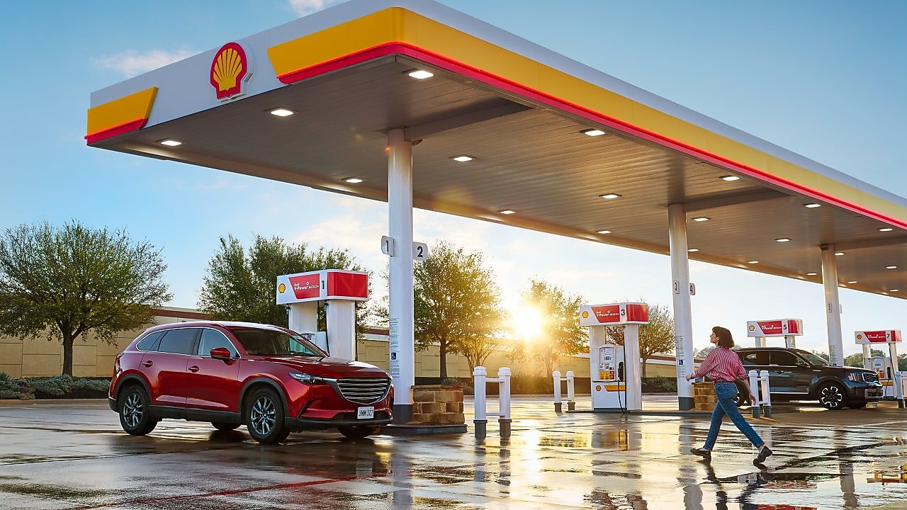 woman walking across the parking lot at a shell station