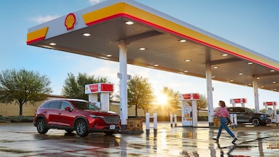 woman walking across the parking lot at a shell station