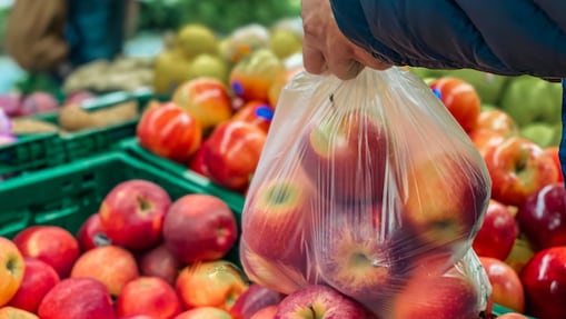 Apples and fruit in a plastic bag being selected in a supermarket by a customer