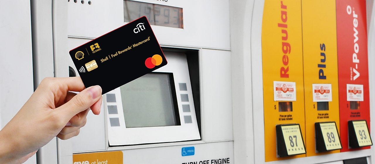 Hand holding credit card at Shell pump