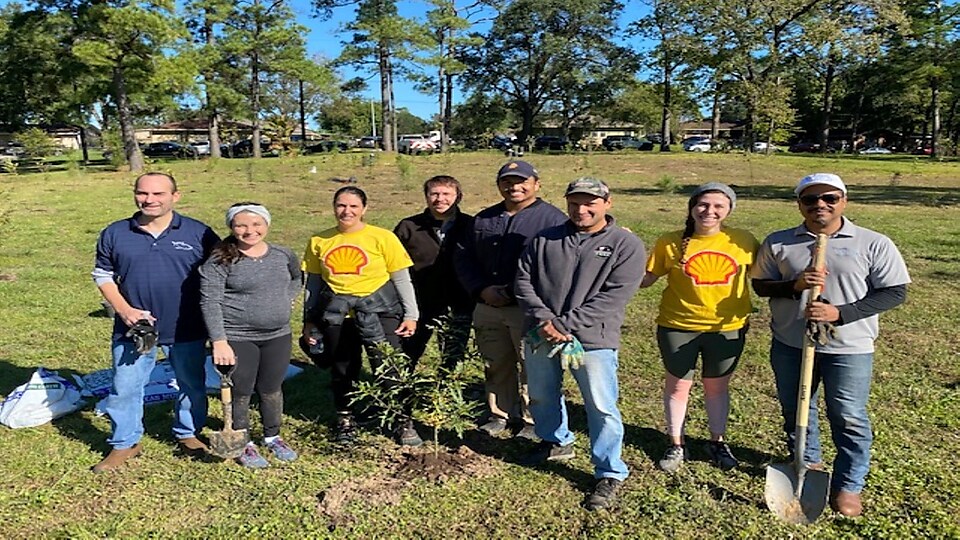 Shell volunteers pose next to freshly planted tree